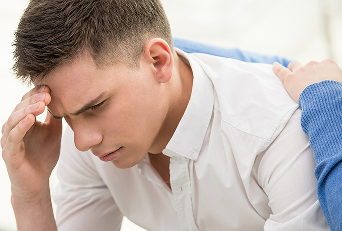 Young man at risk of suicide being comforted by a health professional