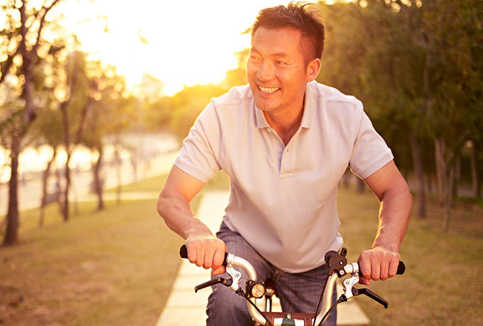 Healthy man riding his bike with sunset