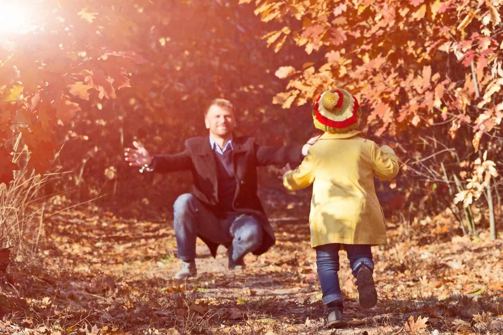 Child running towards father in forest.