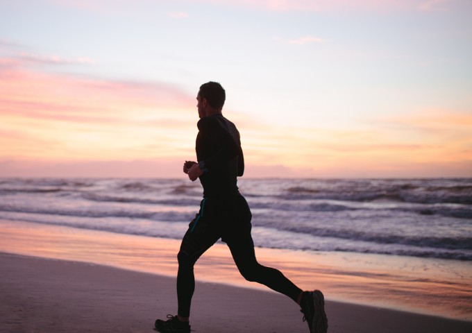Silhouette of man running along the beach at sunrise